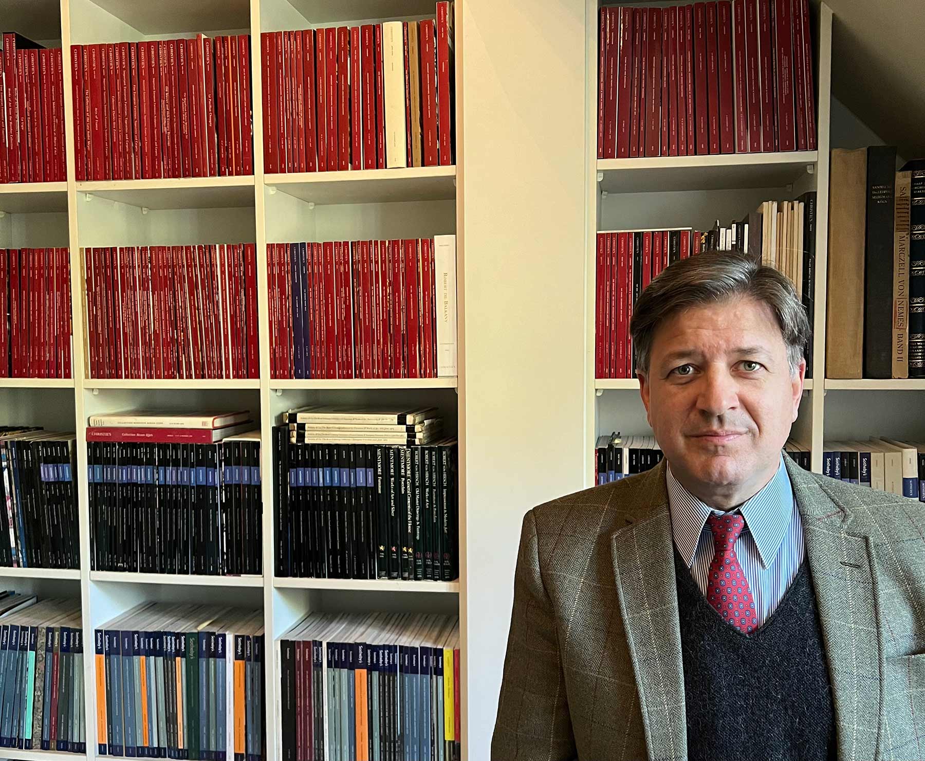 Hubertus Erfurt vor seiner Fachbibliothek mit Auktionskatalogen von Sotheby's und Christie's